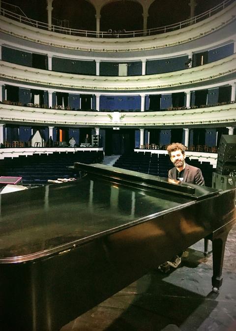 Antonio sentado al piano en el escenario de un teatro vacío